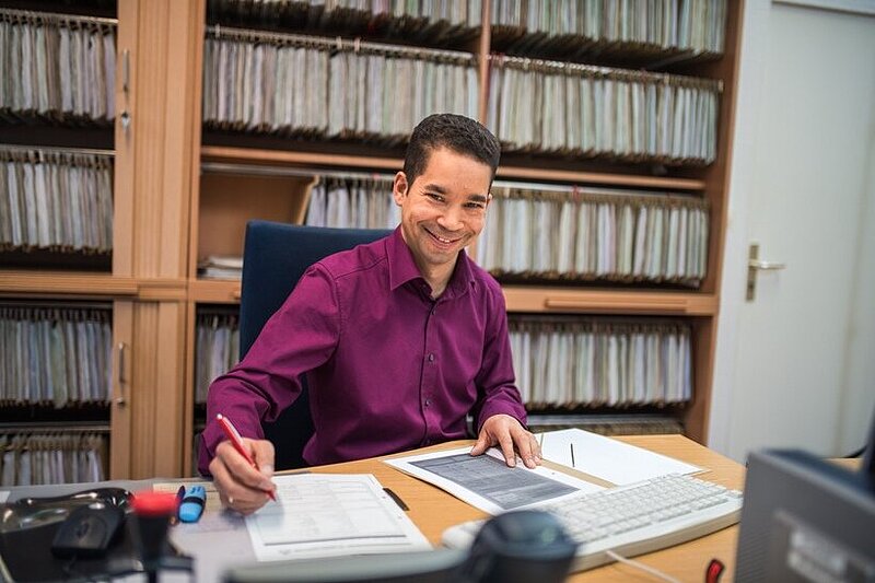 Mitarbeiter arbeitet an einem Schreibtisch und bearbeitet Anträge.