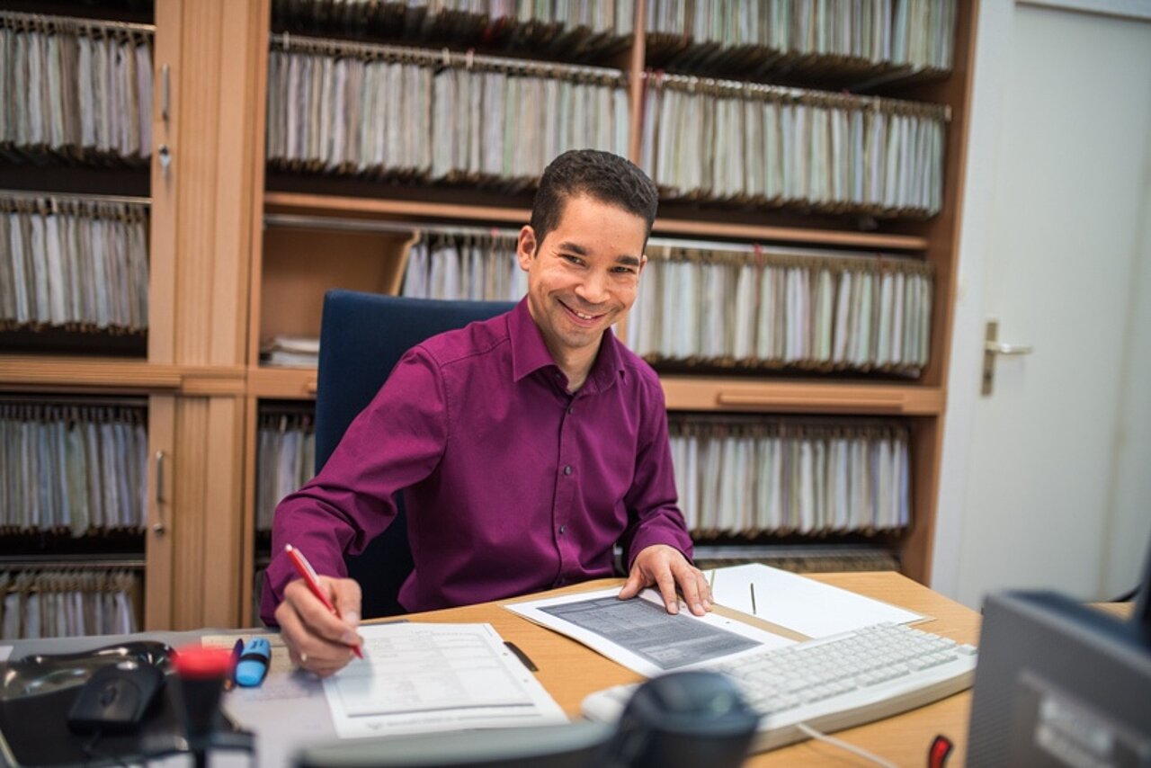 Mitarbeiter arbeitet an einem Schreibtisch und bearbeitet Anträge.