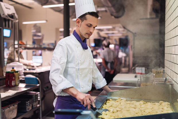 Koch bereitet Speisen in einer Küche zu.